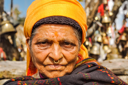 Pathivara Devi, Nepal - circa May 2012: Old wrinkled woman with yellow headcloth and piercing in her...