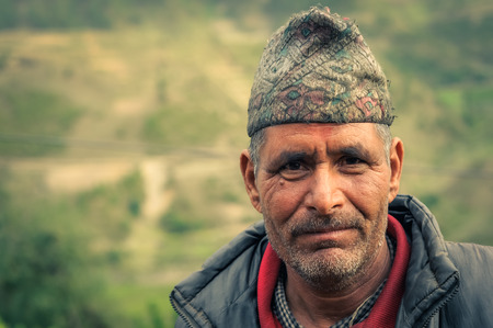 Dolpo, Nepal - circa June 2012: Brown-eyed man with cap dressed in red shirt and grey jacket with beard in Dolpo, Nepal. Documentary editorial.のeditorial素材