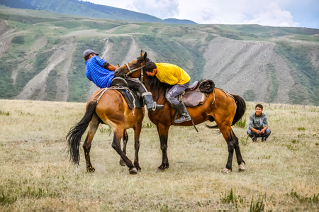 Karakol, Kyrgyzstan - circa July 2011: Young men wrestle at Karakol festival in Kyrgyzstan. Wrestling on horseback belongs to national games in Kyrgystan. Documentary editorial.のeditorial素材