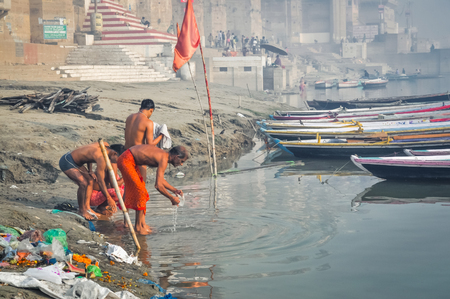 Varanasi, Uttar Pradesh - circa January 2012: Men wash themselves in river during foggy morning in Varanasi, Uttar Pradesh. Documentary editorial.のeditorial素材