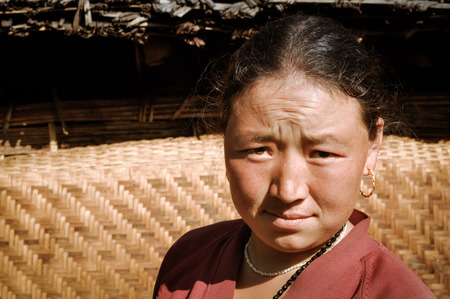 Kanchenjunga Trek, Nepal - circa May 2012: Native woman frowns to photocamera because of sunlight in Kanchenjunga Trek, Nepal. Documentary editorial.のeditorial素材