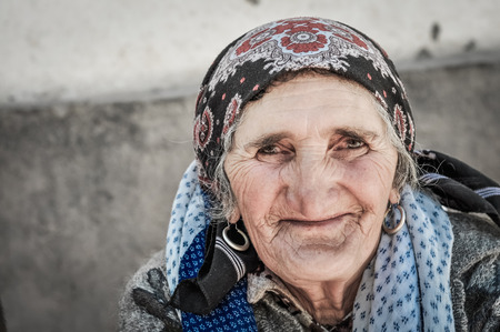 Khorog, Tajikistan - circa September 2011: Older woman with headcloth and earrings smiles nicely to photocamera in Khorog, Tajikistan. Documentary editorial.のeditorial素材