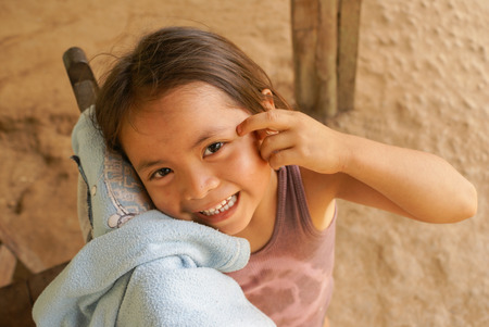 Villa Alcira, Bolivia -circa June 2009: Young smiling girl poses with hand on her face at Villa Alcira, Bolivia. Documentary editorial.のeditorial素材