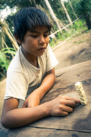 Mashaquipe, Bolivia - circa June 2009: Native boy plays with dice at Mashaquipe, Bolivia. Documentary editorial.のeditorial素材