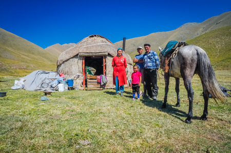 Ala Archa, Kyrgyzstan - circa September 2011: Smiling native family poses with their horse in front of their nomad tent on field in Ala Archa, Kyrgyzstan. Documentary editorial.のeditorial素材