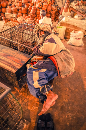 Srimongal, Bangladesh - circa July 2012: Native man with turban sleeps on ground with head on cage with chickens in Srimongal, Bangladesh. Documentary editorial.のeditorial素材