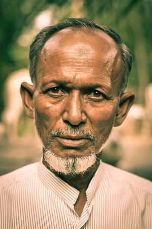Paigacha, Bangladesh - circa July 2012: Native man with brown eyes and short white beard wears white shirt in Paigacha, Bangladesh. Documentary editorial.のeditorial素材