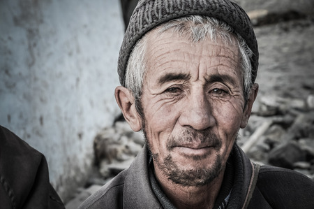 Karakul, Tajikistan - circa September 2011: Smiling man with grey hair and wrinkles on his face poses in Karakul, Tajikistan. Documentary editorial.のeditorial素材