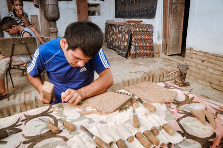 Khiva, Uzbekistan - circa July 2011: Skillful man engraves ornaments into wood in Khiva, Uzbekistan. Documentary editorial.のeditorial素材