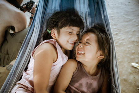 Villa Alcira, Bolivia -circa June 2009: Young smiling girls lie in hammock at Villa Alcira, Bolivia. Documentary editorial.のeditorial素材