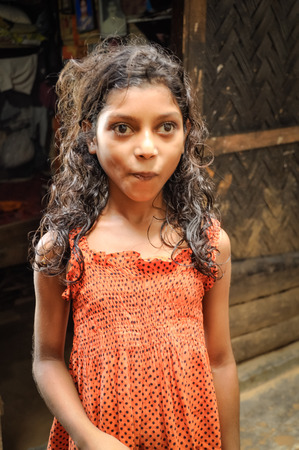 Rangamati, Bangladesh - circa July 2012: Young brown-haired girl in orange dress with dots in street in Rangamati, Bangladesh. Documentary editorial.のeditorial素材