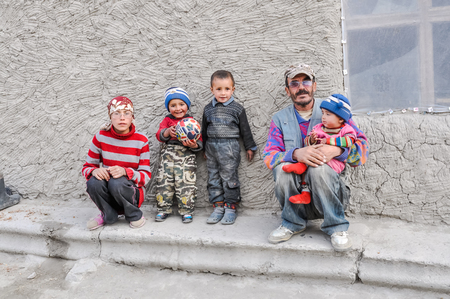 Karakul, Tajikistan - circa September 2011: Man poses with his children dressed in colourful clothes in Karakul, Tajikistan. Documentary editorial.のeditorial素材