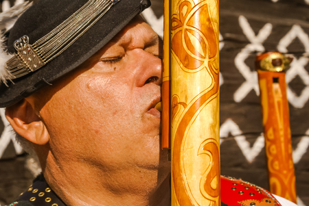 ÄiÄmany, Slovakia - circa September 2009: Man with closed eyes dressed in folk costume plays fujara at Shepherd's pipe folk festival in ÄiÄmany. Documentary editorial.のeditorial素材
