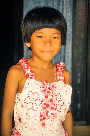 Srimongal, Bangladesh - circa July 2012: Young smiling girl with short black hair dressed in nice white and red dress in Srimongal, Bangladesh. Documentary editorial.のeditorial素材