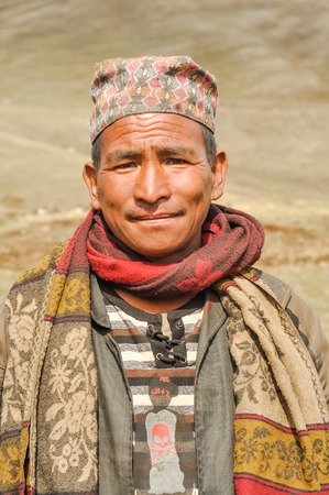 Dolpo, Nepal - circa May 2012: Native man with colourful cap on his head and colourful scarf around neck frowns because of sunshine in Dolpo, Nepal. Documentary editorial.のeditorial素材
