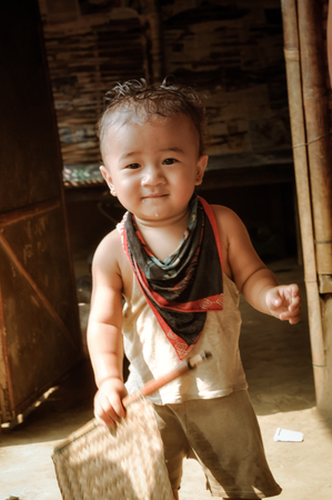 Damak, Nepal - circa May 2012: Small cute boy and holds wooden stick in his hand at Nepali refugee camp in Damak, Nepal. Documentary editorial.のeditorial素材