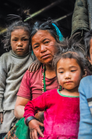 Dolpo, Nepal - circa May 2012: Native black-haired woman with piercing in nose poses with her young daughters and looks down to photocamera in Dolpo, Nepal. Documentary editorial.のeditorial素材