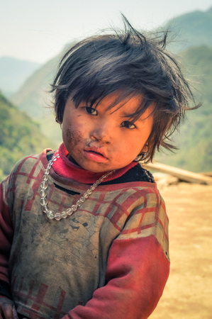 Kanchenjunga Trek, Nepal - circa April 2012: Young girl with brown eyes and small scar on her nose with head on her hands in Kanchenjunga Trek, Nepal. Documentary editorial.のeditorial素材