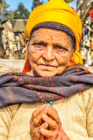 Pathivara Devi, Nepal - circa May 2012: Old woman with yellow headcloth and piercing in her nose with her hands in prayer in Pathivara Devi, Nepal. Documentary editorial.のeditorial素材