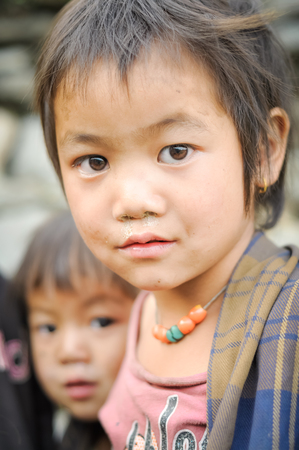 Beni, Nepal - circa May 2012: Small girl with short brown hair and brown eyes wears necklace made of colourful beads in Beni, Nepal. Documentary editorial.のeditorial素材