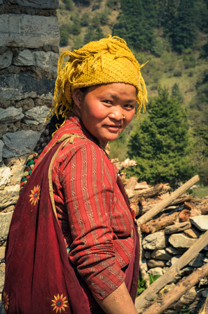 Dolpo, Nepal - circa May 2012: Smiling native woman with long hair and with yellow headcloth wears red clothes in Dolpo, Nepal. Documentary editorial.のeditorial素材