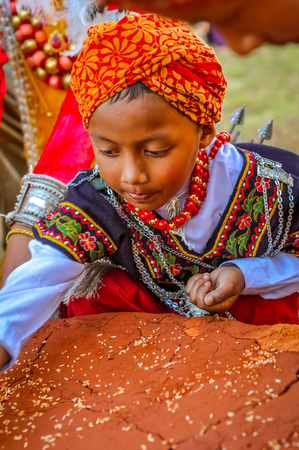 Shillong, Meghalaya - circa April 2012: Small boy with turban wears traditional costume and kneels during game at Shad Suk Mynsiem Festival in Shillong, Meghalaya. Documentary editorial.のeditorial素材