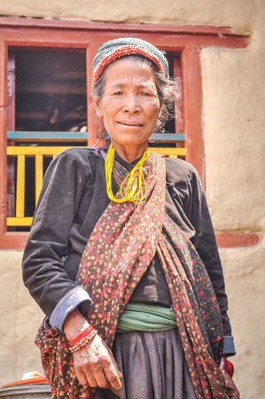 Dolpo, Nepal - circa May 2012: Old woman with headcloth wears black shirt, scarf and yellow necklace in Dolpo, Nepal. Documentary editorial.のeditorial素材