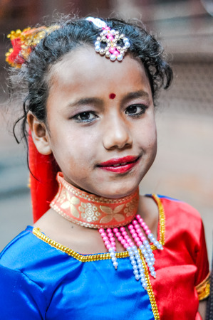 Kathmandu, Nepal - circa May 2012: Young girl in blue and red costume with necklace and red dot on her forehead has white powder on her skin in Kathmandu, Nepal. Documentary editorial.のeditorial素材