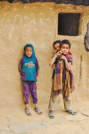 Dolpo, Nepal - circa May 2012: Three young boys pose to photocamera in front of their house and one of them shows symbol of peace on his hand in Dolpo, Nepal. Documentary editorial.のeditorial素材