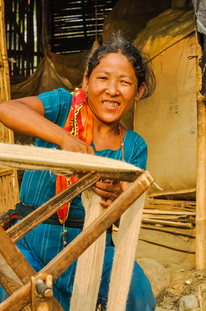 Damak, Nepal - circa May 2012: Native woman in blue clothes and colourful scarf works outside at Nepali refugee camp in Damak, Nepal. Documentary editorial.のeditorial素材
