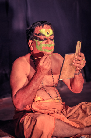 Ernakulam, Kerala - circa February 2012: Man paints his face with colours at See India Foundation and prepares for Kathakali, classical Indian dance-drama in Ernakulam, Kerala. Documentary editorial.のeditorial素材