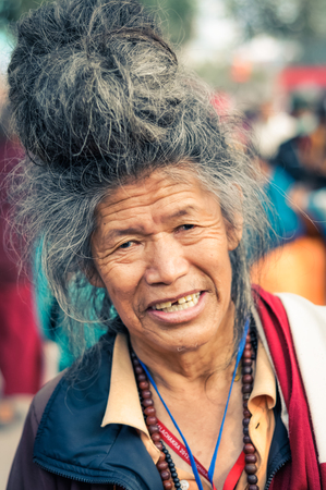 Bohdgaya, Bihar - circa January 2012: Older man with big hairdo and missing front tooth during teachings in Bohdgaya, Bihar. Documentary editorial.のeditorial素材