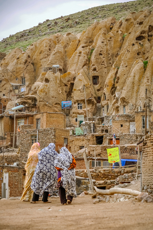 Kandovan, Iran - circa June 2011: Women n scarves look at rock houses in rocky village of Kandovan in Iran. Documentary editorial.のeditorial素材