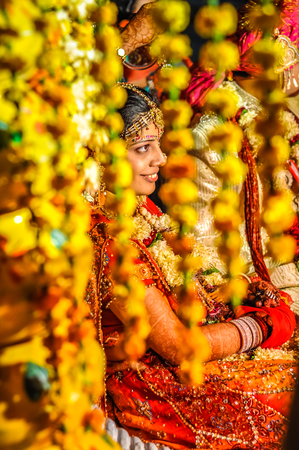 Bikaner, Rajasthan - circa December 2011: Photo of smiling bride behind yellow decorations during wedding ceremony in Bikaner, Rajasthan. Documentary editorial.のeditorial素材
