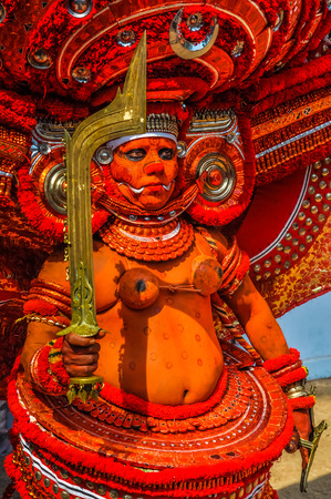 Thottada, south of Kannur, Kerala - circa January 2012: Photo of beautiful and artistic mask of young ritual dancer at Theyyam near Thottada, Kerala. He holds golden sword. Documentary editorial.のeditorial素材
