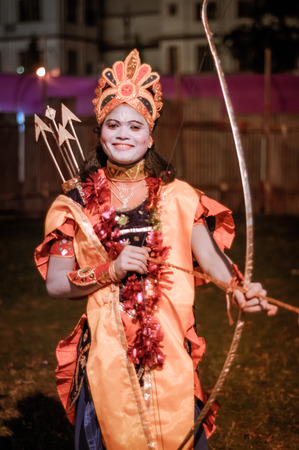 Guwahati, Assam - circa April 2012: Girl in yellow costume with crown holds bow and arrow with colours on her face at Bihu festival in Guwahati, Assam. Documentary editorial.のeditorial素材