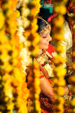 Bikaner, Rajasthan - circa December 2011: Young smiling bride sits behind yellow decorations during her wedding in Bikaner, Rajasthan. Documentary editorial.のeditorial素材