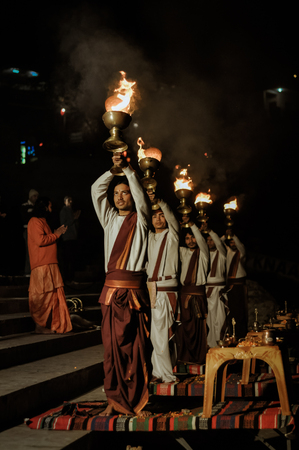 Rishikesh, Uttarakhand - circa January 2012: Young men stand in row and hold golden goblets with burning candles above their heads during ceremony in Rishikesh, Uttarakhand. Documentary editorial.のeditorial素材