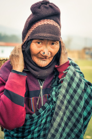 Ziro, Arunachal Pradesh - circa March 2012: Apatani woman with typical tattoo and large nose plugs carries wicker basket in Ziro, Arunachal Pradesh. Documentary editorial.のeditorial素材