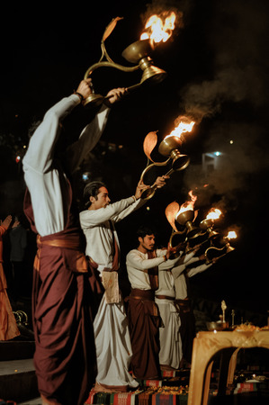 Rishikesh, Uttarakhand - circa January 2012: Young men stand and hold golden goblets with burning candles during ceremony in Rishikesh, Uttarakhand. Documentary editorial.のeditorial素材