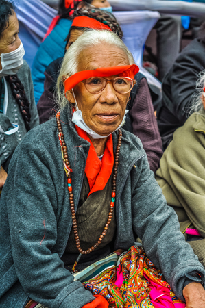 Bohdgaya, Bihar - circa January 2012: Old woman with beads on her neck and grey hair wears glasses and red stripe around her head during teachings in Bohdgaya, Bihar. Documentary editorial.のeditorial素材