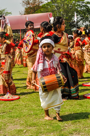 Guwahati, Assam - circa April 2012: Small boy in red and white costume plays drum during performance at Bihu festival in Guwahati, Assam. Documentary editorial.のeditorial素材