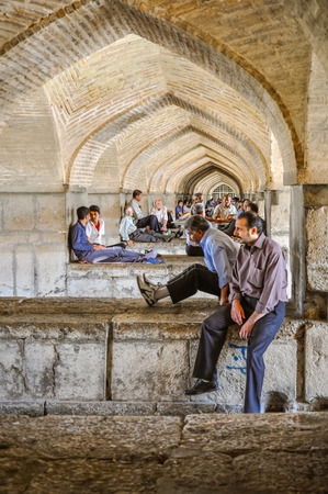 Esfahan, Iran - circa June 2011: Men sit below stone arches in Iran's third largest city, Esfahan. Documentary editorial.のeditorial素材