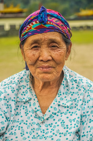Tuting, Arunachal Pradesh - circa March 2012: Old native woman in white and blue shirt and with colourful headcloth in Tuting, Arunachal Pradesh. Documentary editorial.のeditorial素材
