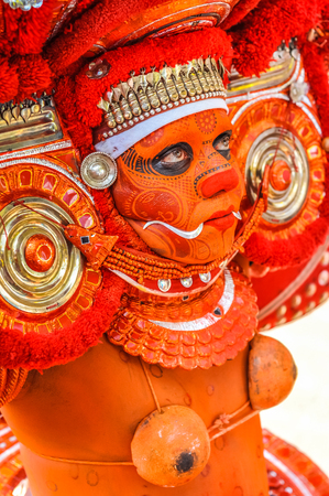 Thottada, south of Kannur, Kerala - circa January 2012: Native man in orange and red mask and costume looks up at Theyyam near Thottada, south of Kannur, Kerala. Documentary editorial.のeditorial素材