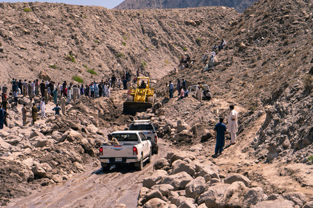 Karakoram Highway, Pakistan - July 19, 2018: People watching recovery works after landslide destroyed dangerous mountain road in Karakoram mountains, Pakistan. Illustrative editorial.のeditorial素材