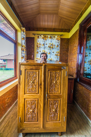 Young man in Indian sauna that looks like wardrobe with only his head sticking out of it.のeditorial素材