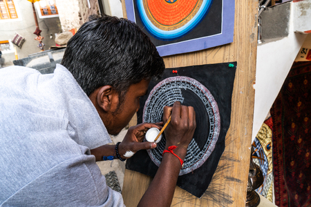 Leh, India - August 24, 2018: Man drawing a circular buddhist symbol in the streets of Leh. Illustrative editorial.のeditorial素材