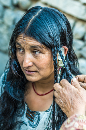 Ladakh, India - August 29, 2018: Indigenous elderly woman in Ladakh, India, having her hair done for an upcoming festival. Illustrative editorial.のeditorial素材