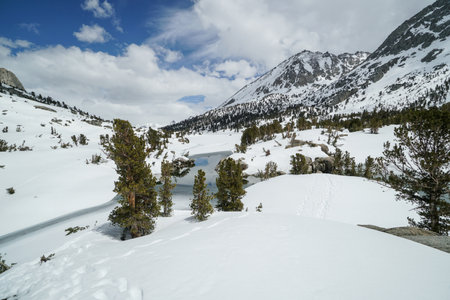 Pacific Crest Trail. A snowy mountain range with a river running through it. The snow is deep and the trees are bare. The scene is peaceful and sereneの写真素材
